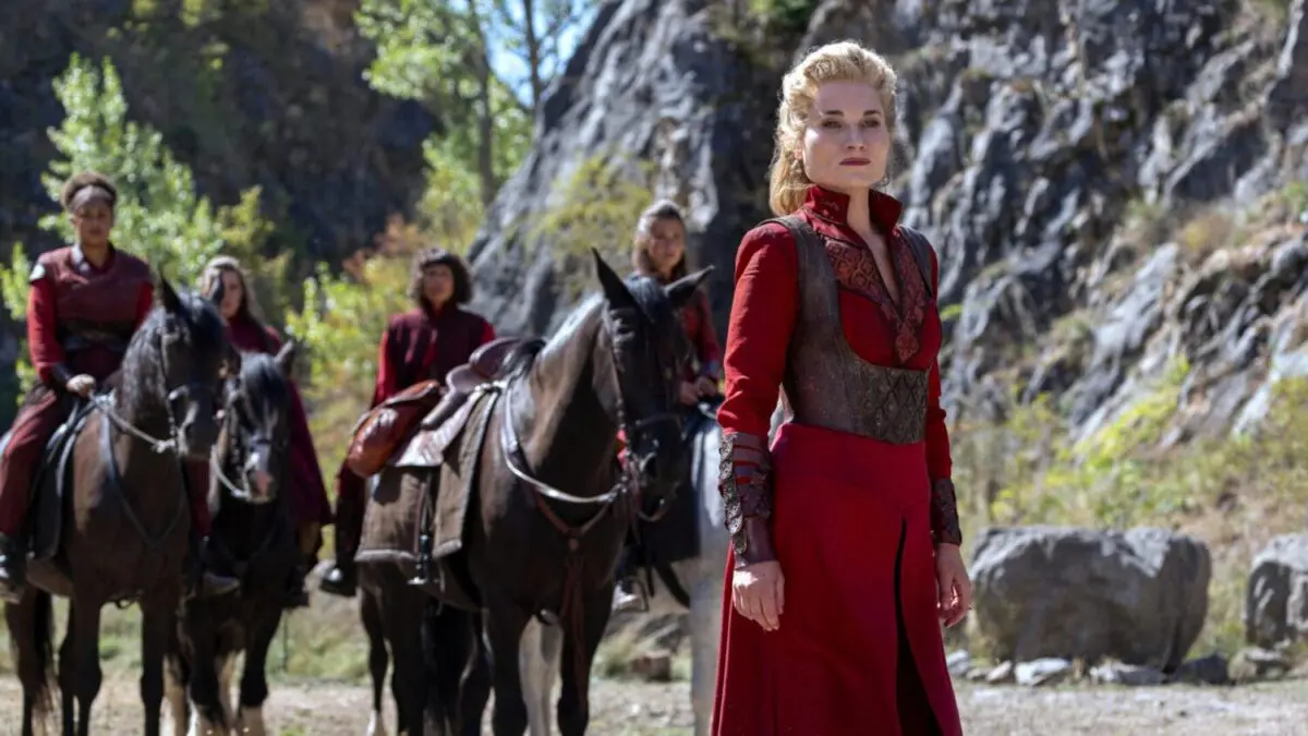 A group of women in red stand outside, some on horses