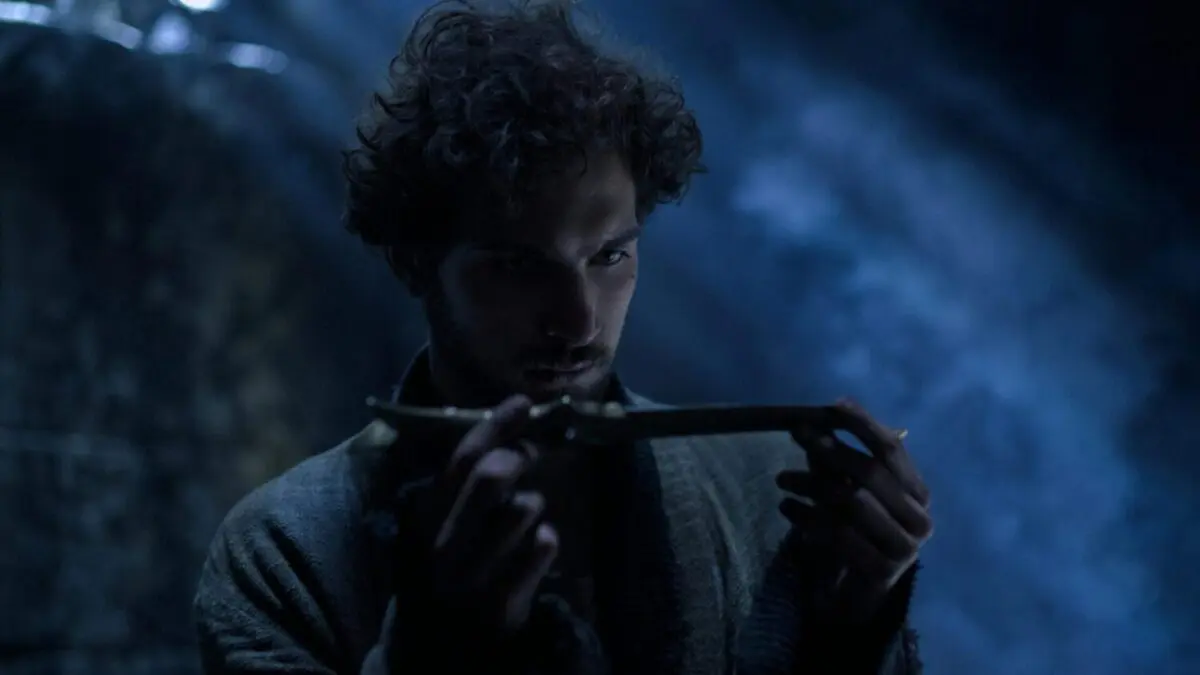 Barney Harris as Mat, picking up a ruby-hilted dagger in a dark room.