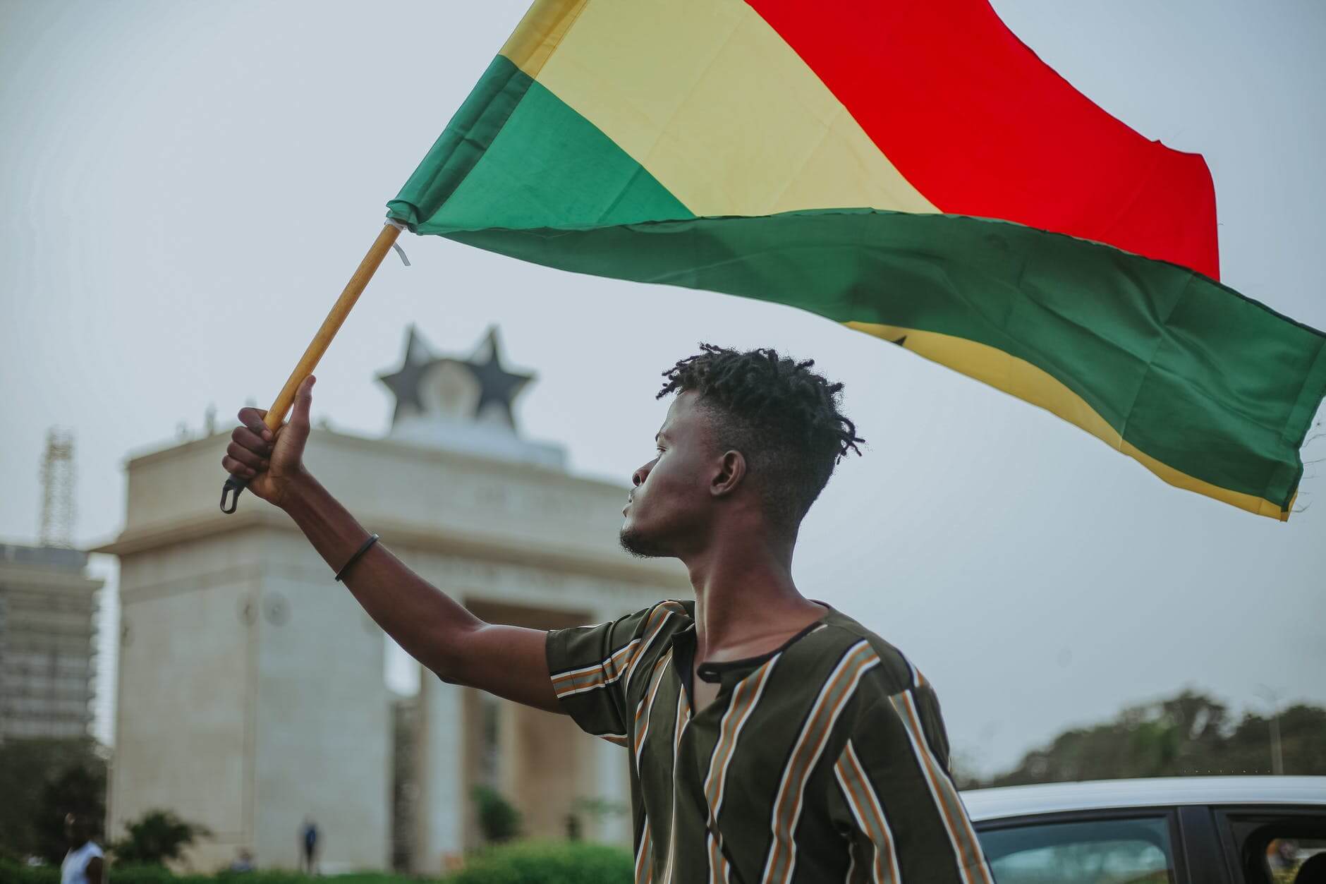 black man with flag of ghana on city street