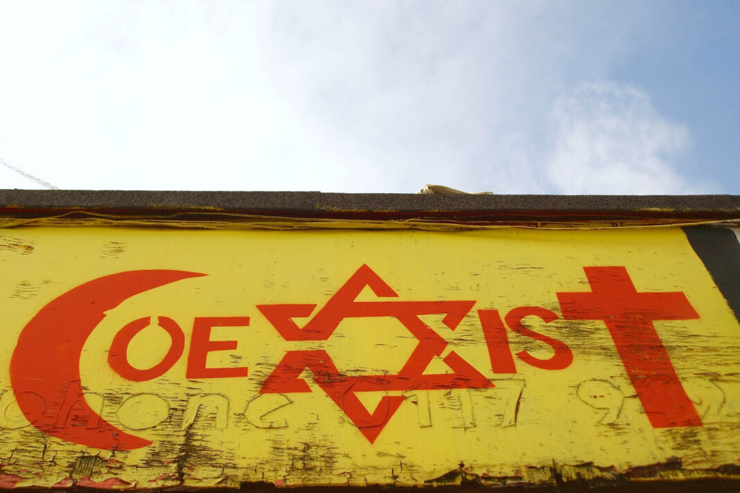 View of a religious tolerance themed graffiti piece by an unidentified artist on a city center building in Bristol, UK.