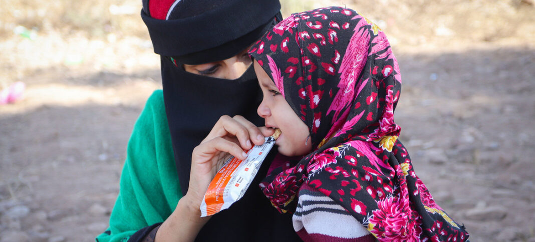 WFP/Saleh Bin Haiyan 'n Ma voer haar dogter 'n voedingsstafie wat sy van 'n mobiele gesondheidskliniek in Jemen ontvang het.