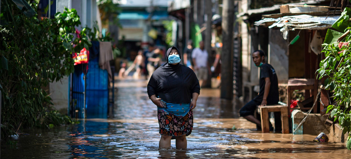 A woman walks through water in an area affected by flooding in East Jakarta, Indonesia.