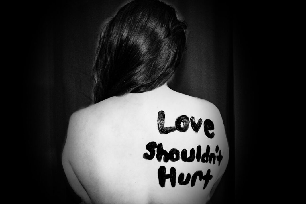 woman showing back with message love shoulnt hurt