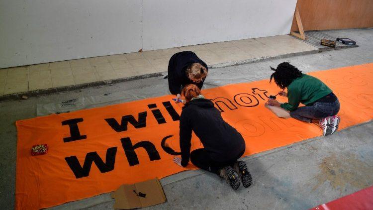 Activists on the island of Lesbos prepare a banner reading "I will not reject anybody who will come to me" on the eve of the Pope's visit