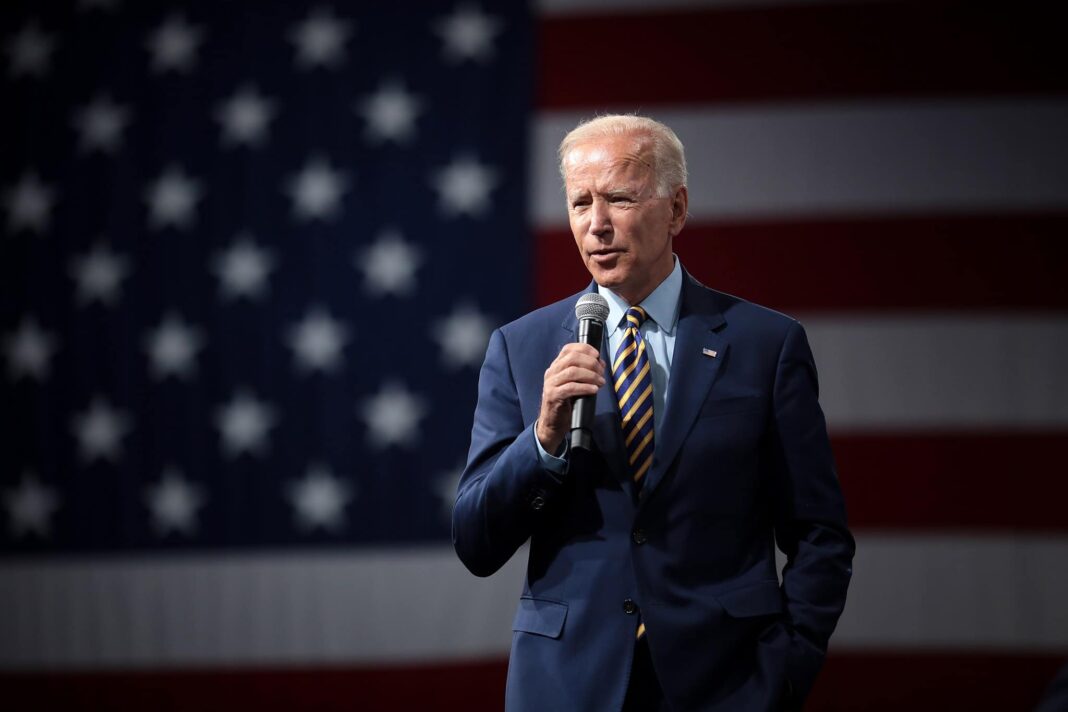 Joe Biden con bandera estadounidense en la espalda