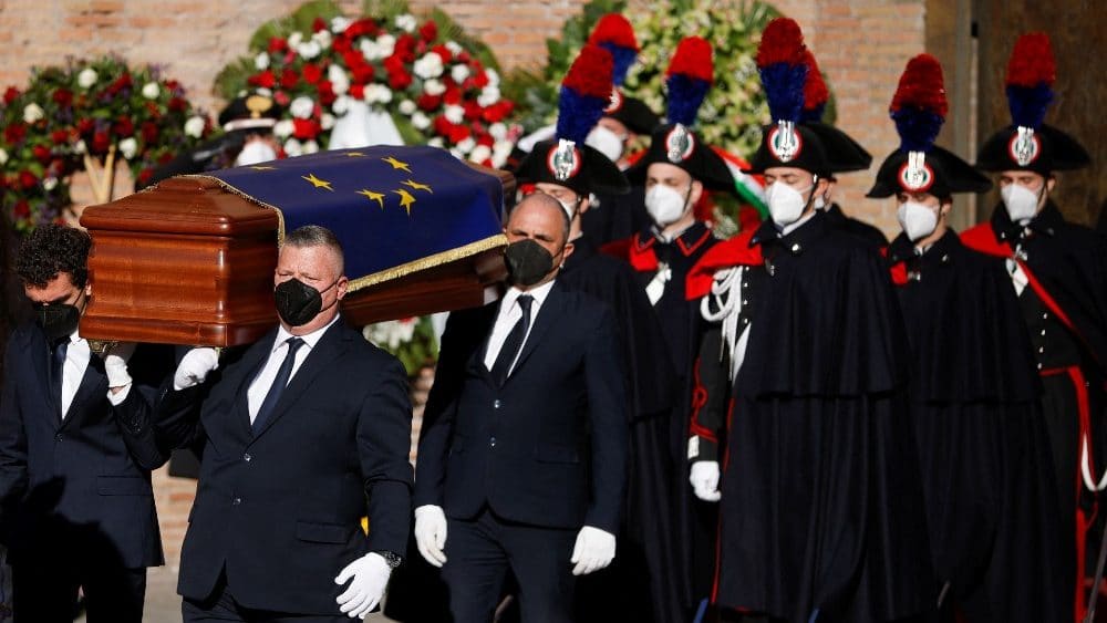 des hommes en costumes noirs portent un cercueil qui porte le drapeau de l'union européenne