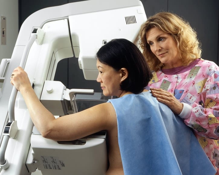 a woman is being breast cancer screened a doctor is behind her