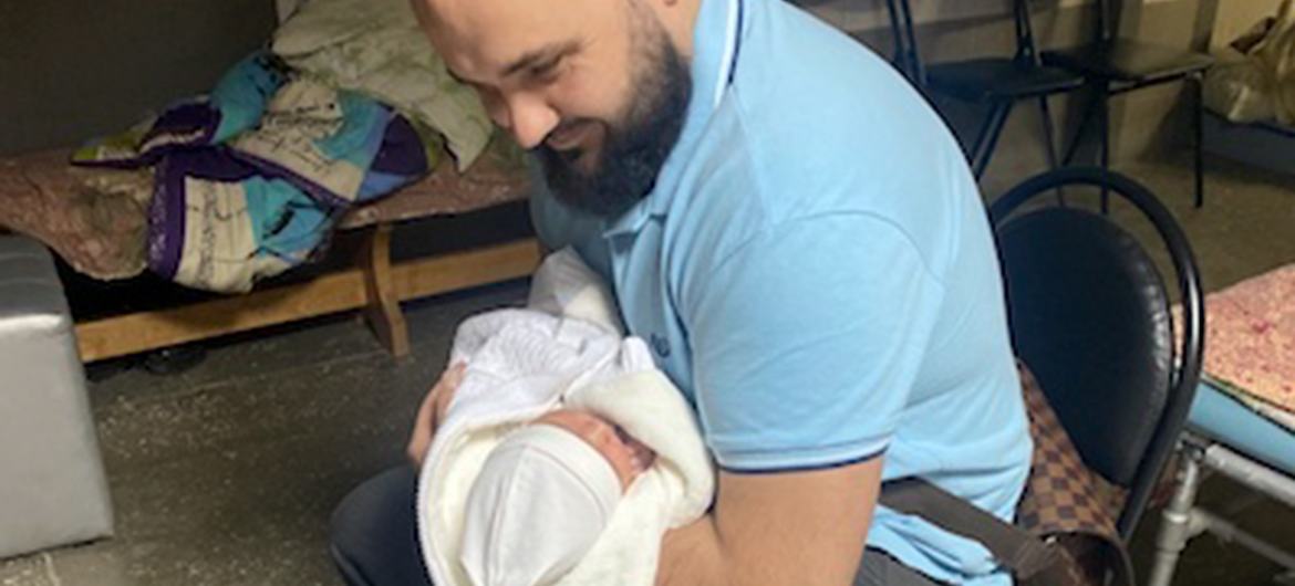 Ms. Shostak's husband, Yurii, holds his new son at the hospital. They plan to stay in the basement of their home for now.