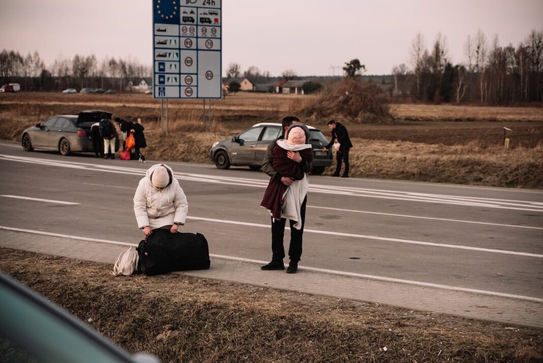 a woman sitting on the side of a road next to a luggage bag