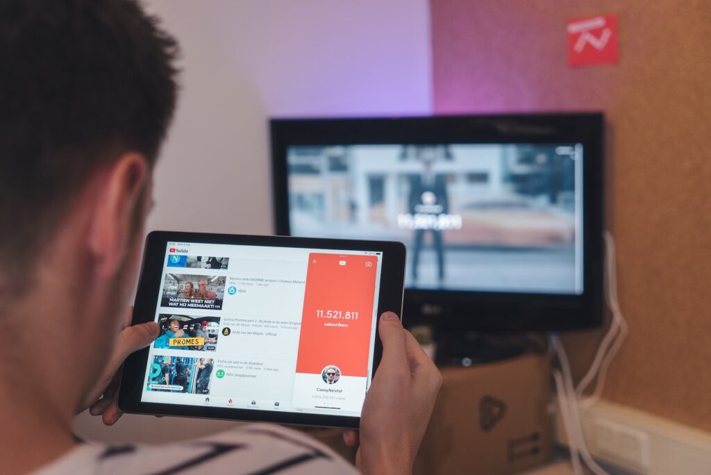youtube-man die op een tablet surft en tv zit