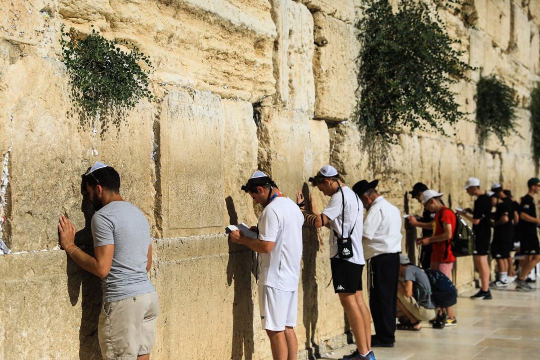 un groupe de personnes debout à l'extérieur avec le Mur Occidental en arrière-plan