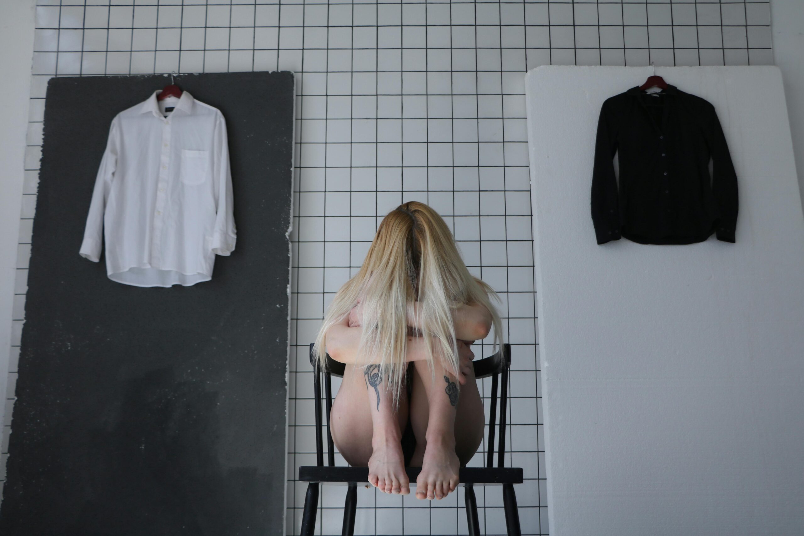 photo/anonymous-frustrated-woman-sitting-on-chair-behind-tiled-wall-4603576/